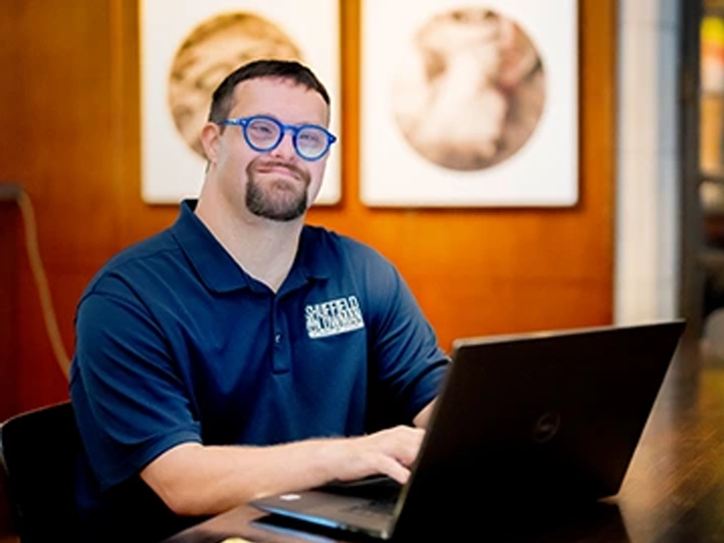 Man using a laptop at a table in an office