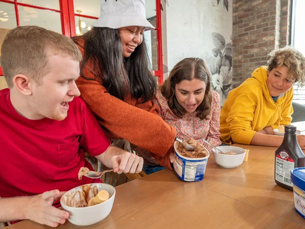 Four friends sharing ice cream at a table